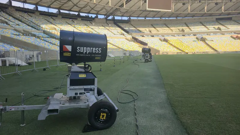 Dois canhões de névoa Suppress sobre rodas à beira do gramado do Maracanã, com as arquibancadas ao fundo